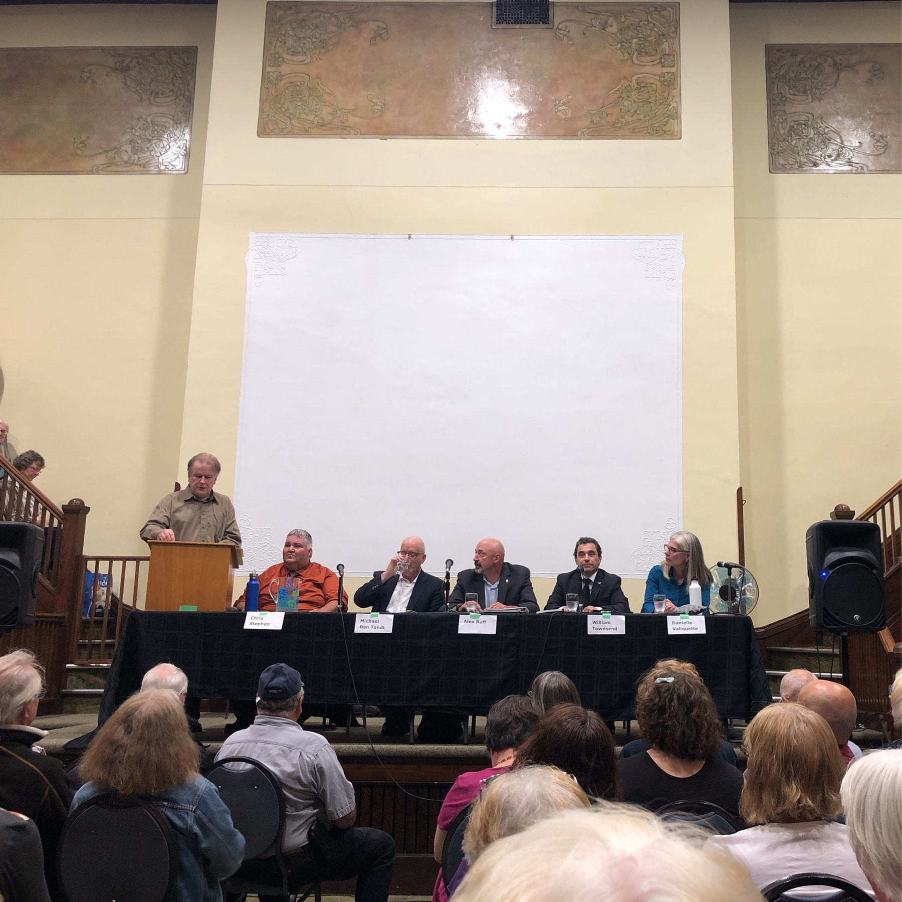 five candidates and a moderator  face the audience 