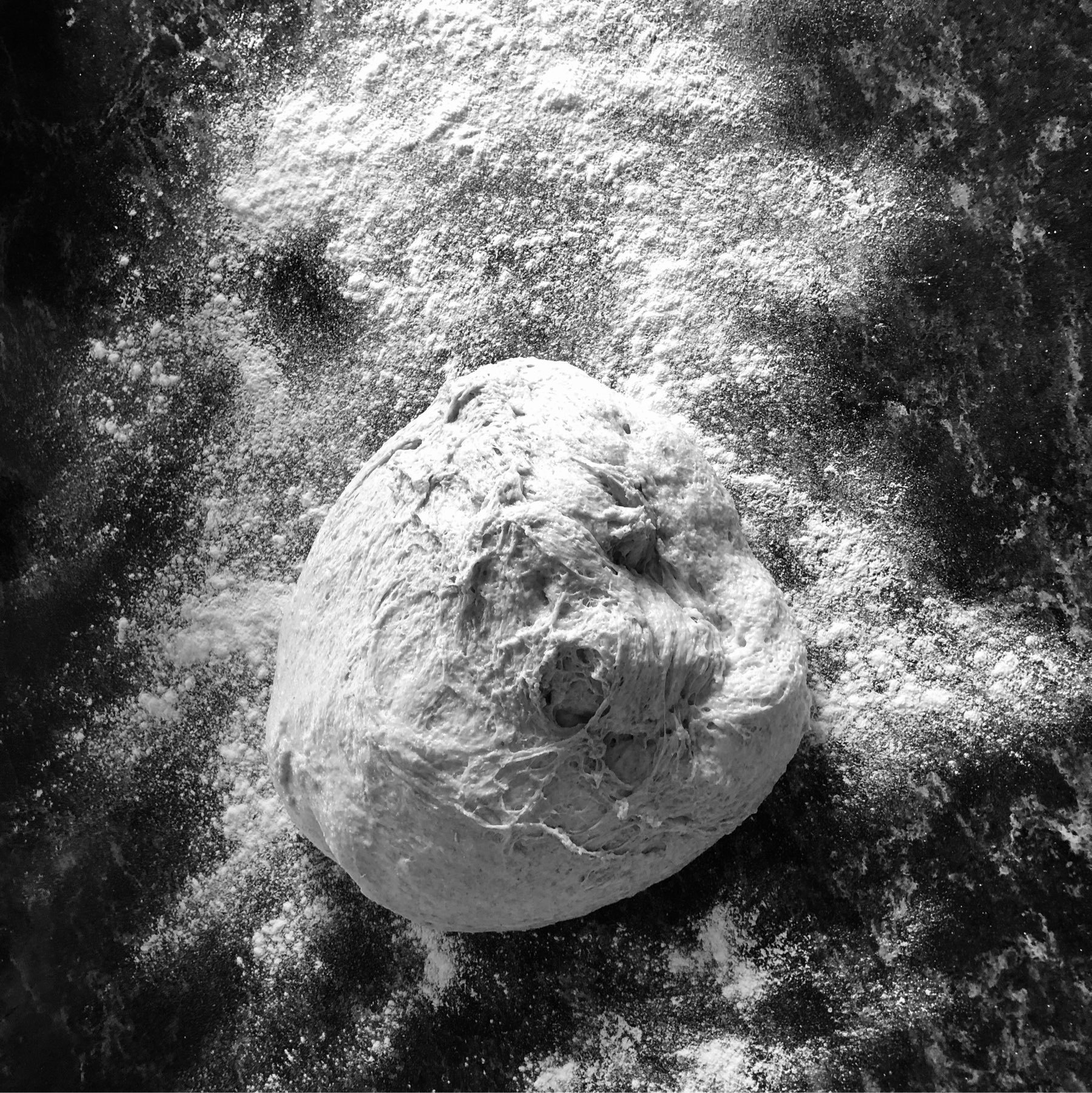 a black and white photo of a large ball of dough sitting on a countertop covered in flour