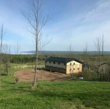 house sitting in the middle of bare soil. view of Georgian Bay in the background