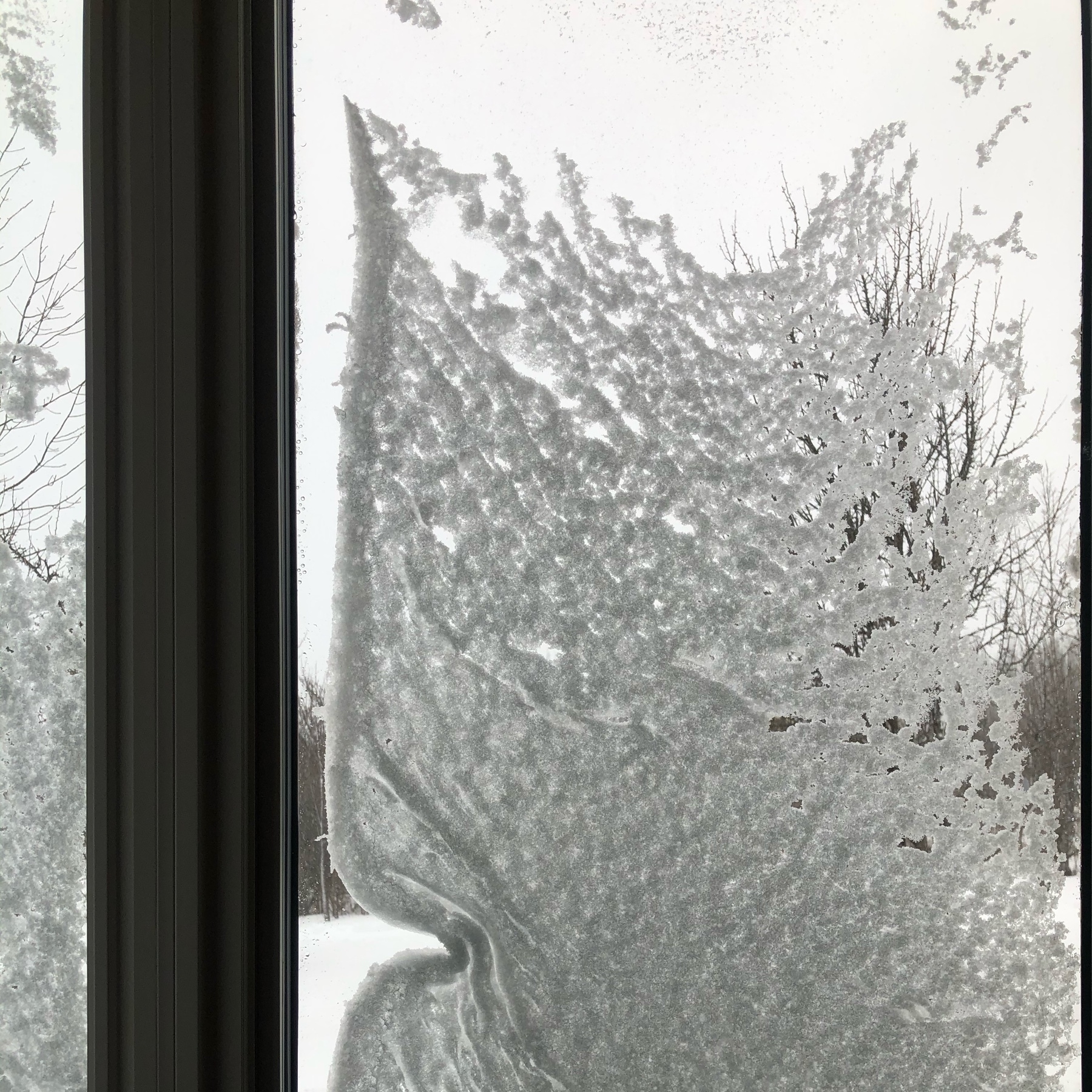 snow on outside of a window. the snow has melted away from one edge