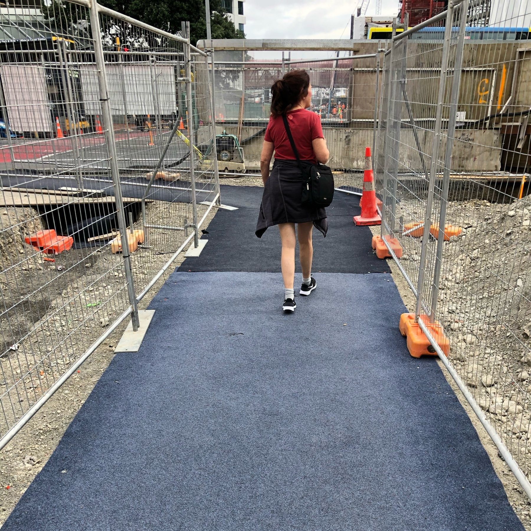 lady walking in construction area surrounded by construction fencing