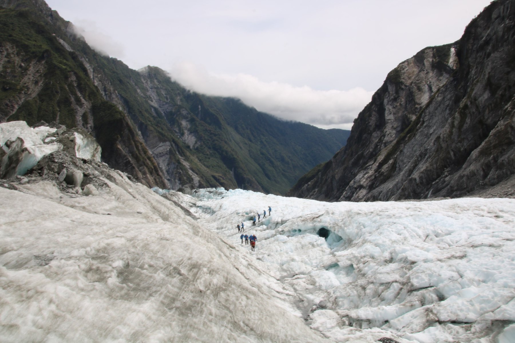 a group of people on a glacier. mountains in the background