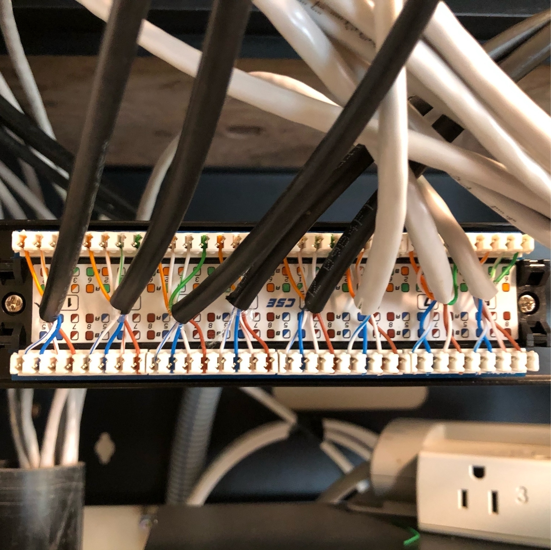 5 black and 3 white cat5e cables connected to terminals behinds a patch panel