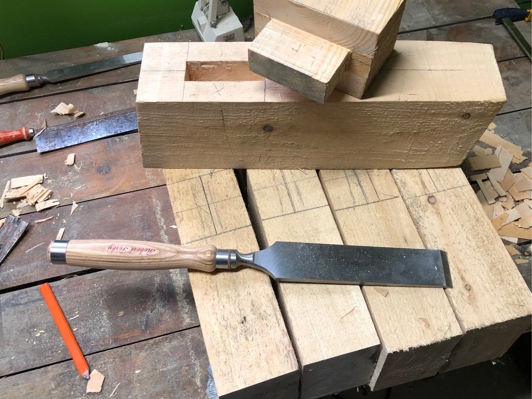 pine chunks eoth a mortise and tenon joint. four other pieces marked for cutting