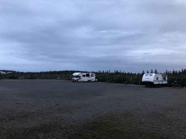 a trailer and a motorhome in a gravel parking lot