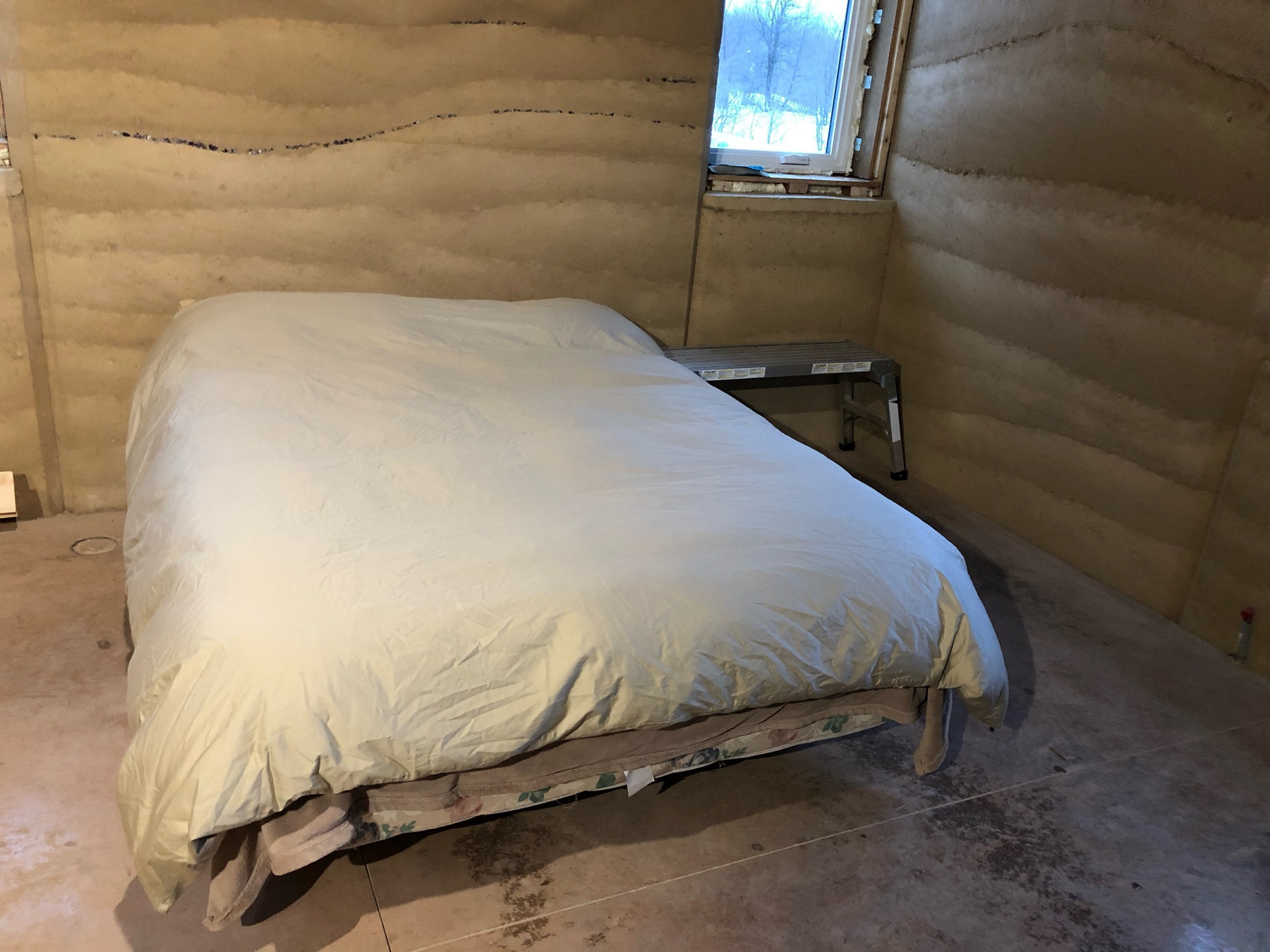 a bed in a room with gold, wavy walls. there is a window in the corner