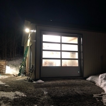 a garage door full of foggy windows just after dark. there is a little snow on the ground.