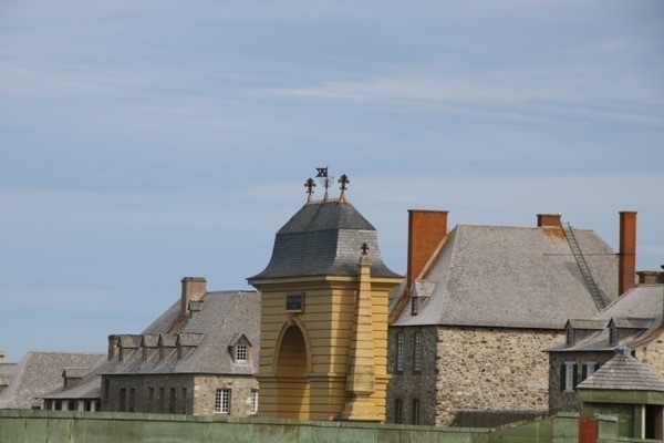 multiple old buildings including a yellow tower above a stone wall