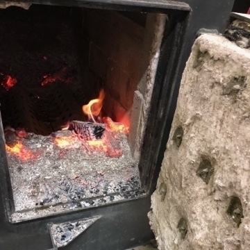 an open door to a firebox with a few coals burning