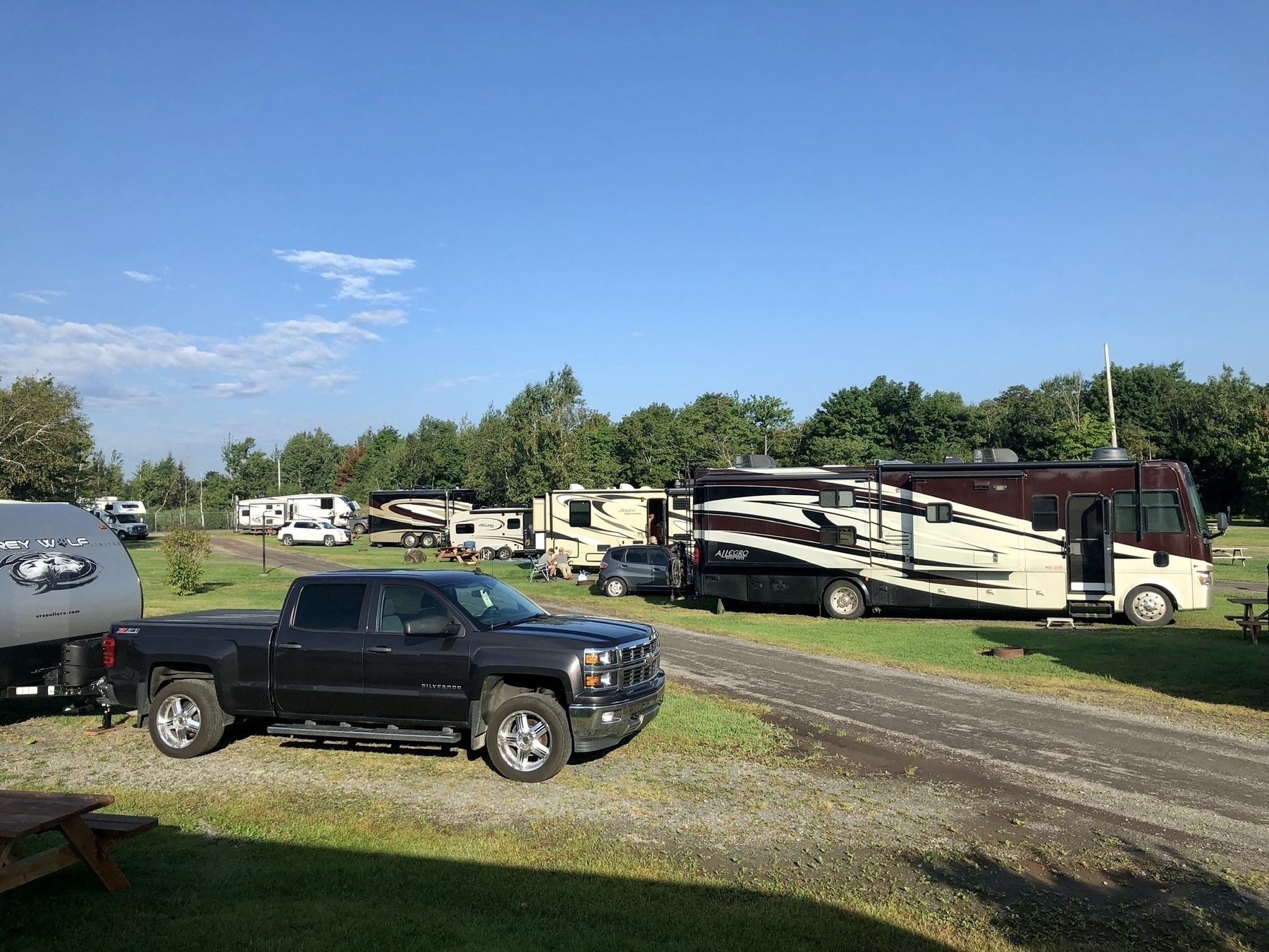 row of fifth wheel trailers and motorhomes on grass