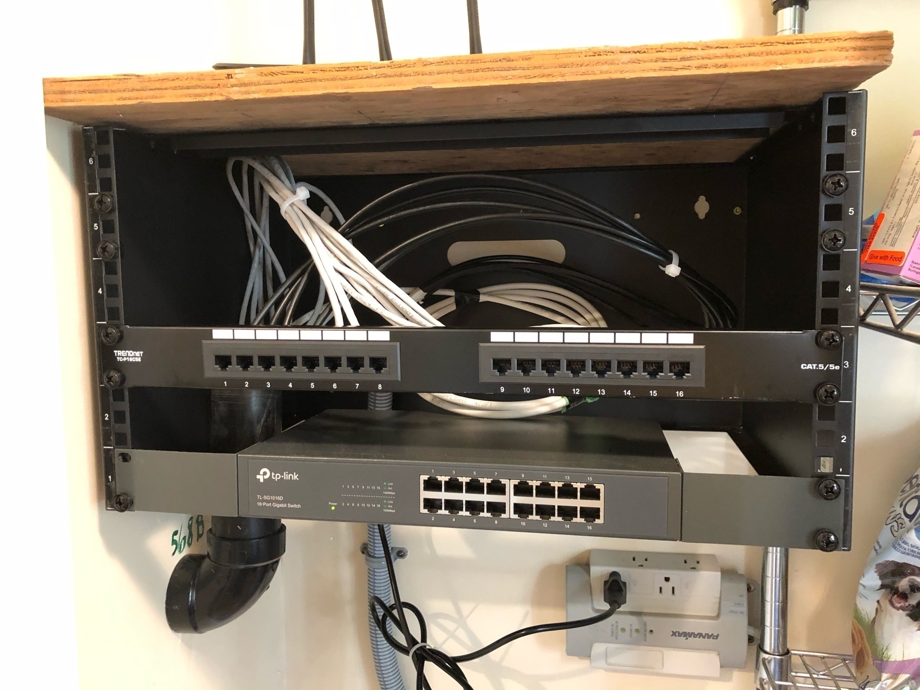 16 port patch panel installed over a switch with multiple cables bundled behind