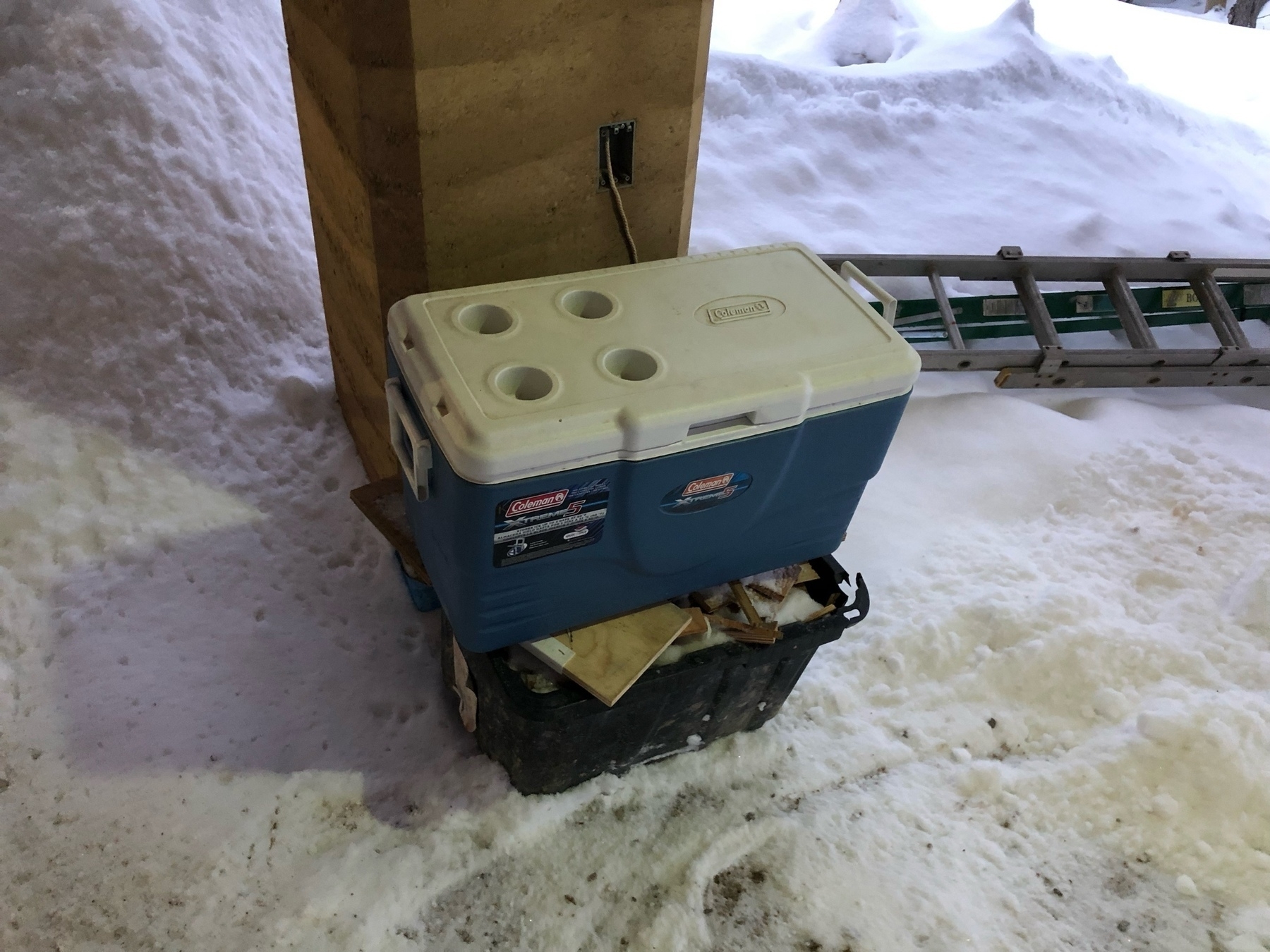 a large blue cooler sitting on a black tote in front of a column