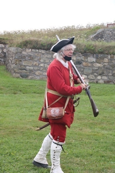 soldier in costume explaining the operation of a musket