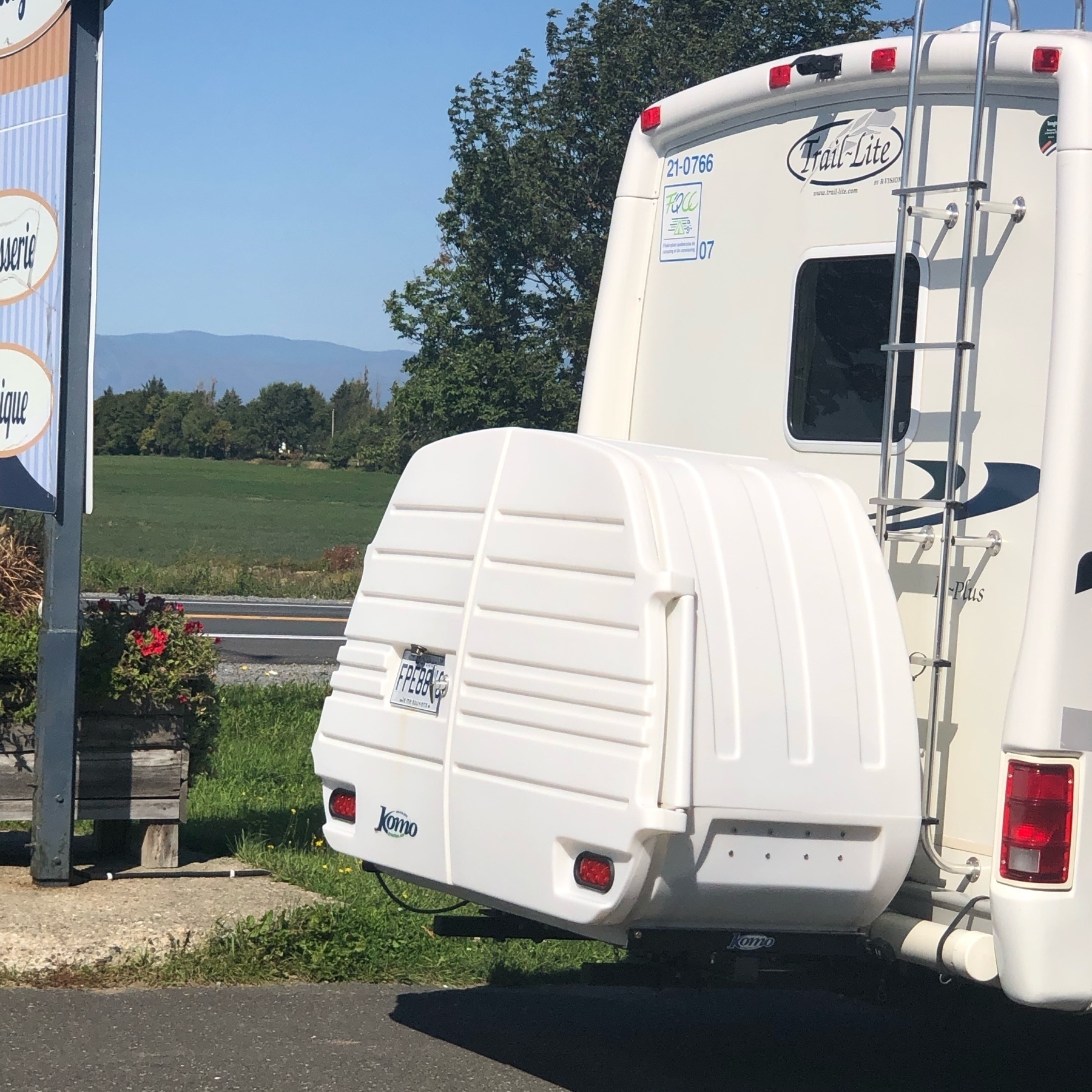 white plastic enclosure for a bicycle on tje nack of a little rv